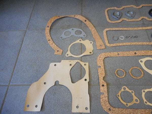 Motorpakkingset with various gaskets displayed on a tiled surface. Motorpakkingset with various gaskets displayed on a tiled surface.