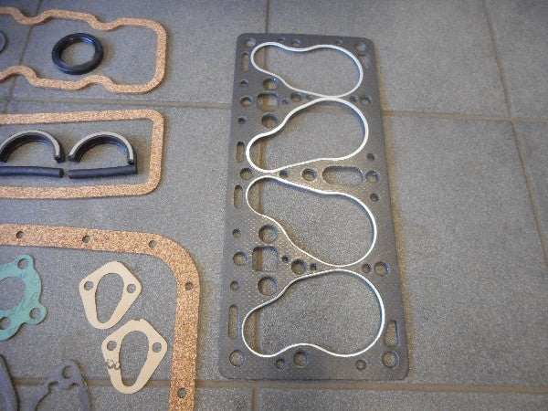 Motorpakkingset with various gaskets displayed on a tiled surface. Motorpakkingset with various gaskets displayed on a tiled surface.